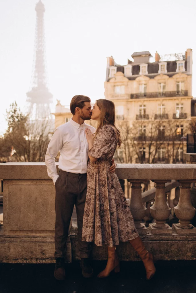 Newlywed couple kissing during a Paris honeymoon photoshoot with the Eiffel Tower in soft golden light